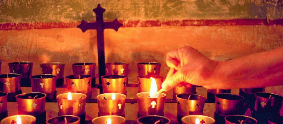 Worshiper Lighting Votive Candle on Altar