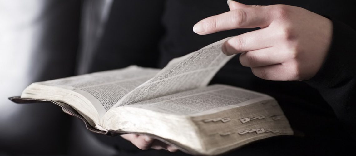 Woman sits in a sofa and read the Bible
